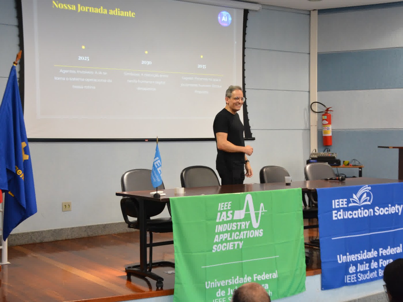 Marcos Alves, CEO of Hal-AI, delivering his talk at ENTENSE 2026 in the UFJF auditorium, in front of the IEEE IAS and IEEE Education Society banners.